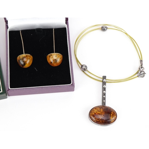 2582 - Silver mounted amber jewellery comprising two pendants on chains and two pairs of earrings