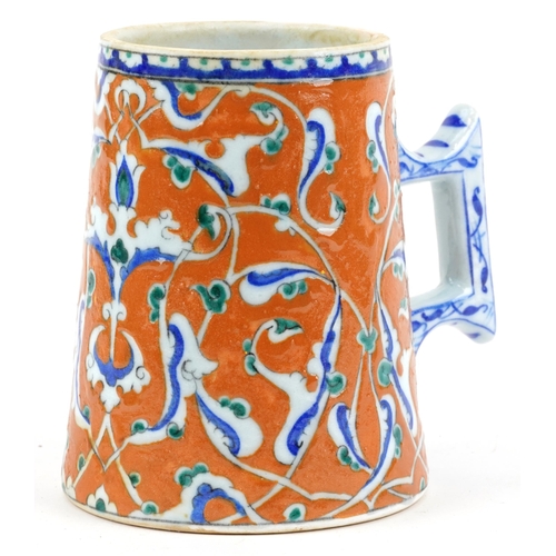 277 - Turkish Ottoman Iznik tankard with tapering body hand painted with stylised flowers, 15.5cm high