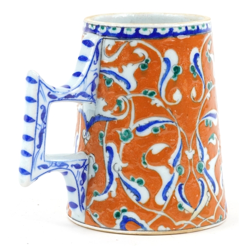 277 - Turkish Ottoman Iznik tankard with tapering body hand painted with stylised flowers, 15.5cm high