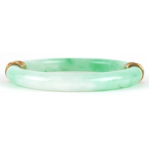 41 - Chinese green jade bangle with unmarked gold mounts decorated in relief with dragons, 9.5cm in diame... 