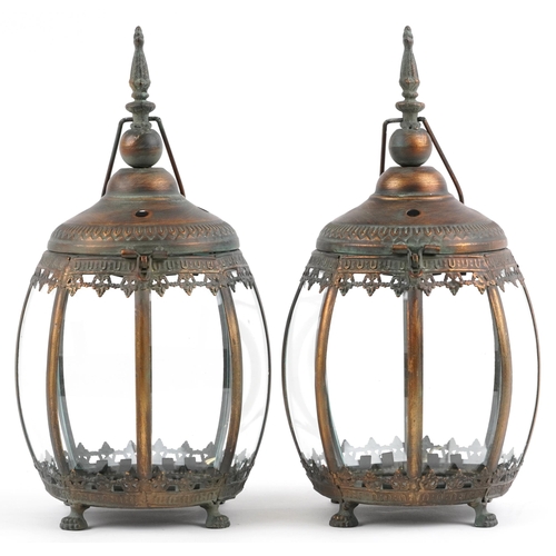 2551 - Pair of bronzed hanging lanterns with glass panels on paw feet, each 39.5cm high