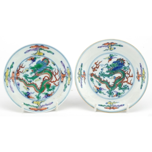 303 - Two Chinse doucai porcelain dishes, each hand painted with a dragon chasing the flaming pearl amongs... 