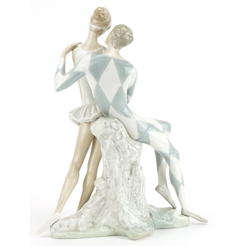 2244 - Lladro porcelain Idyl figure group in the form of Harlequin seated on a tree stump beside a ballerin... 