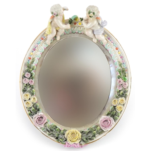 246 - Dresden, German porcelain oval easel floral encrusted mirror having bevelled glass surmounted with t... 