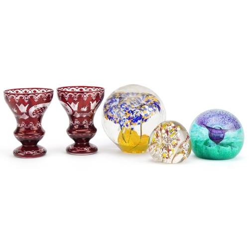 2493 - Pair of Czech Egermann ruby overlaid etched glass vases and three colourful glass paperweights, the ... 