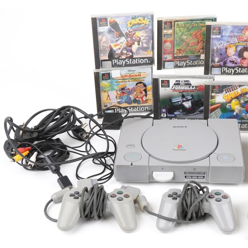 1219 - Three Sony PlayStation games consoles with controllers and various games including Crash Bandicoot