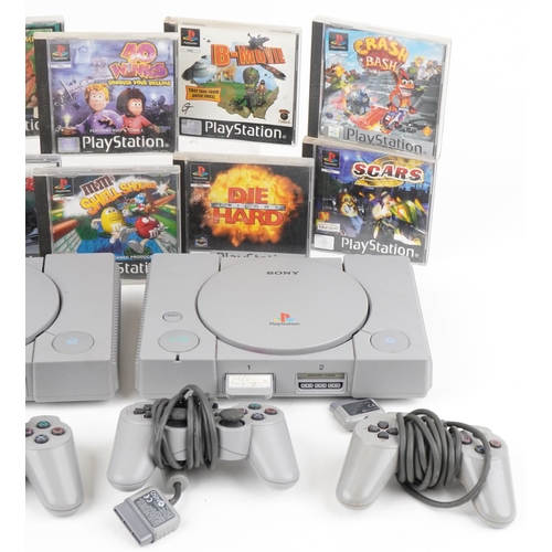 1219 - Three Sony PlayStation games consoles with controllers and various games including Crash Bandicoot