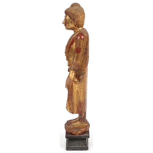 72 - Thai floor standing red lacquered gilt painted figure of standing Buddha, 105cm high PROVENANCE: Loc... 