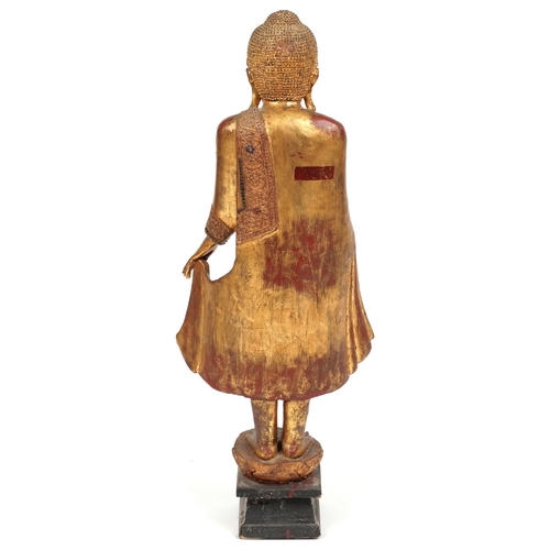 72 - Thai floor standing red lacquered gilt painted figure of standing Buddha, 105cm high PROVENANCE: Loc... 