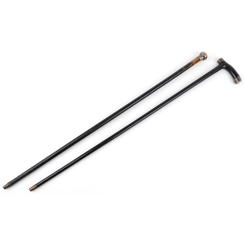 664 - Two ebonised walking sticks with silver mounts and brass ferules, the largest 86cm in length