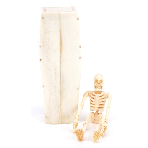 711 - Scrimshaw style carved bone skeleton housed in a bone coffin with lift off lid, the coffin 11.5cm in... 