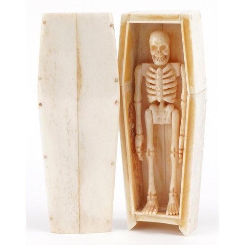 711 - Scrimshaw style carved bone skeleton housed in a bone coffin with lift off lid, the coffin 11.5cm in... 