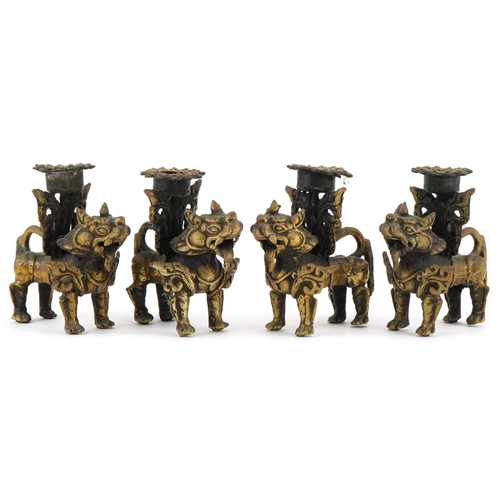 681 - Two pairs of Tibetan gilt metal candlesticks in the form of Foo dogs, each 10cm high