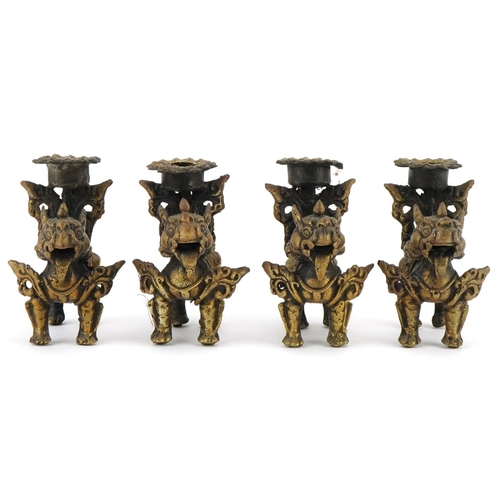 681 - Two pairs of Tibetan gilt metal candlesticks in the form of Foo dogs, each 10cm high