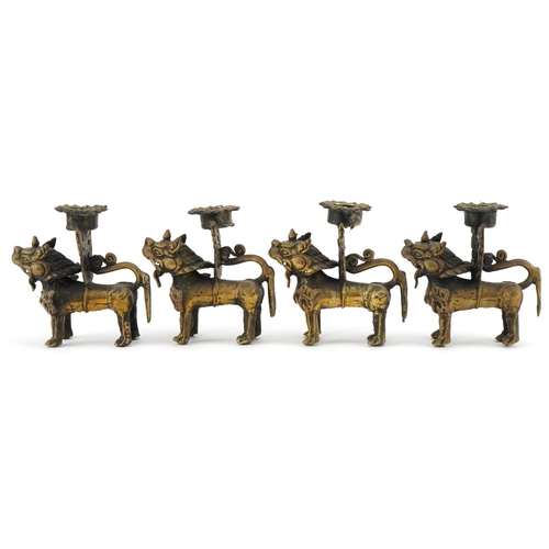 681 - Two pairs of Tibetan gilt metal candlesticks in the form of Foo dogs, each 10cm high