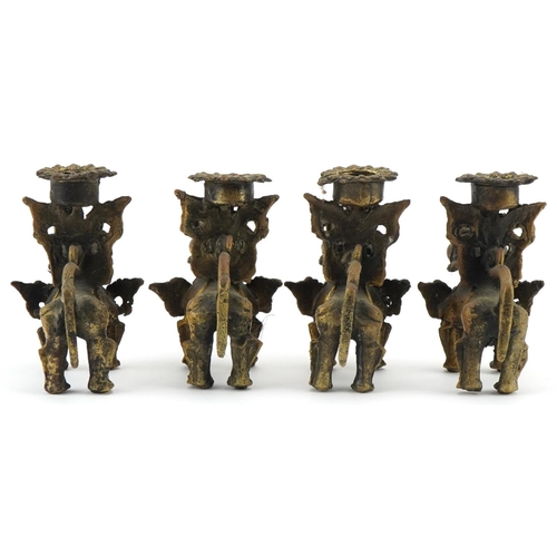 681 - Two pairs of Tibetan gilt metal candlesticks in the form of Foo dogs, each 10cm high