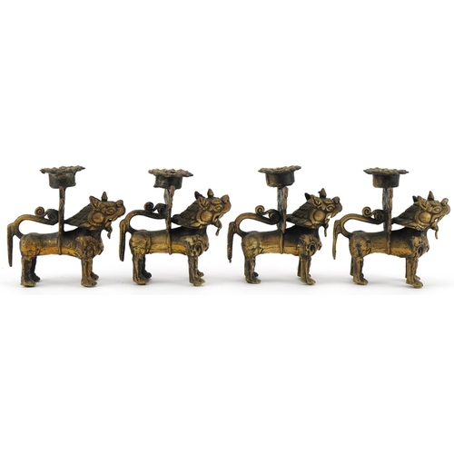 681 - Two pairs of Tibetan gilt metal candlesticks in the form of Foo dogs, each 10cm high