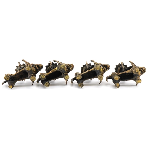 681 - Two pairs of Tibetan gilt metal candlesticks in the form of Foo dogs, each 10cm high