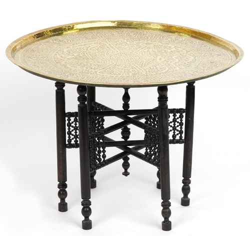 2145 - Islamic brass tray top tea table profusely engraved with panels of calligraphy on Moorish style ebon... 