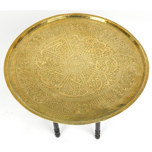 2145 - Islamic brass tray top tea table profusely engraved with panels of calligraphy on Moorish style ebon... 