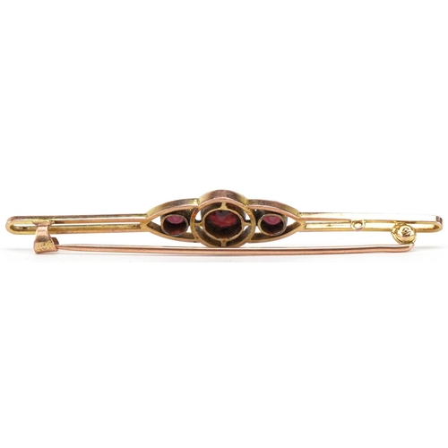 3164 - 9ct gold garnet three stone openwork bar brooch, 6.5cm wide, 4.2g