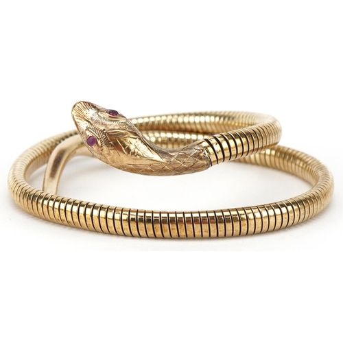 3068 - 9ct gold and steel serpent bangle with ruby eyes, 7cm in diameter, 31.2g