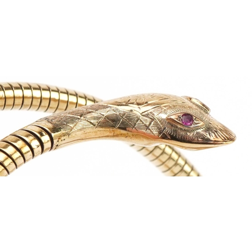 3068 - 9ct gold and steel serpent bangle with ruby eyes, 7cm in diameter, 31.2g