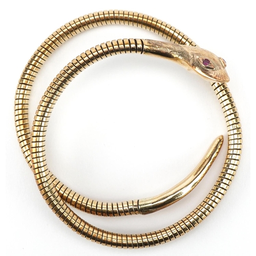 3068 - 9ct gold and steel serpent bangle with ruby eyes, 7cm in diameter, 31.2g