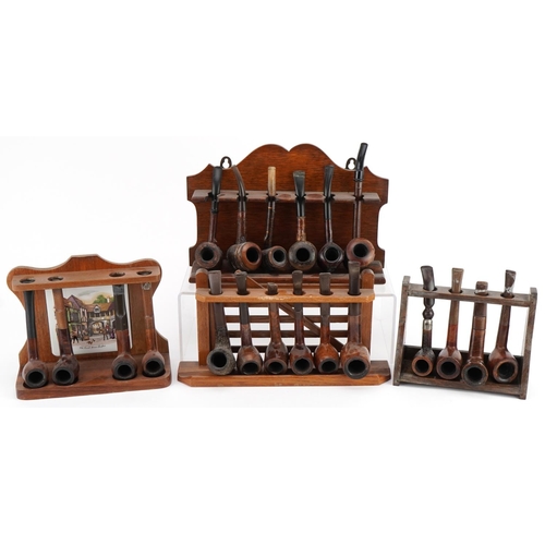 1298 - Twenty vintage briar tobacco smoking pipes arranged in four pipe racks, one in the form of a gate, i... 