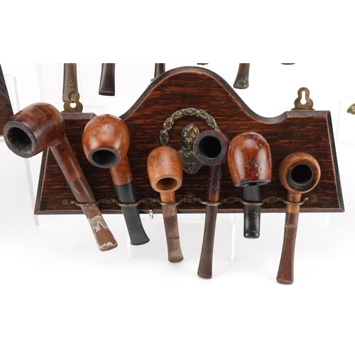 1282 - Twenty two vintage briar tobacco smoking pipes arranged in four wall hanging pipe racks, two with Sm... 