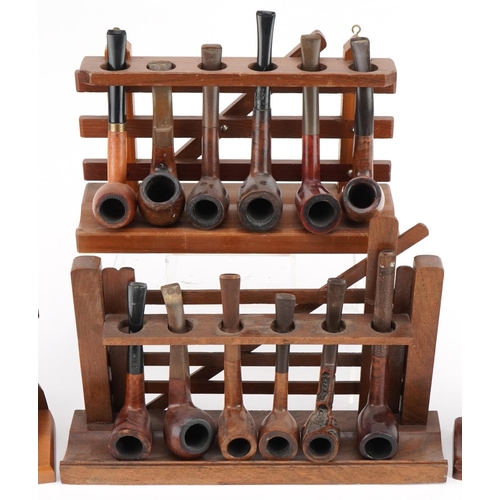 1289 - Twenty vintage tobacco smoking pipes, predominantly briar, arranged in four pipe racks comprising th... 