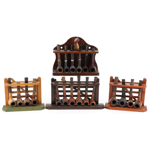 1290 - Twenty vintage briar tobacco smoking pipes arranged in four pipe racks including three in the form o... 