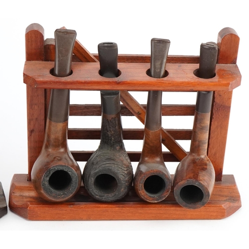 1290 - Twenty vintage briar tobacco smoking pipes arranged in four pipe racks including three in the form o... 