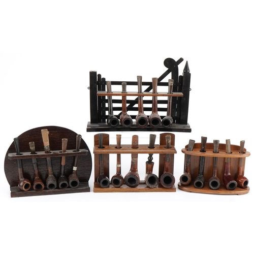 1277 - Twenty vintage briar tobacco smoking pipes arranged in four pipe stands including one in the form of... 