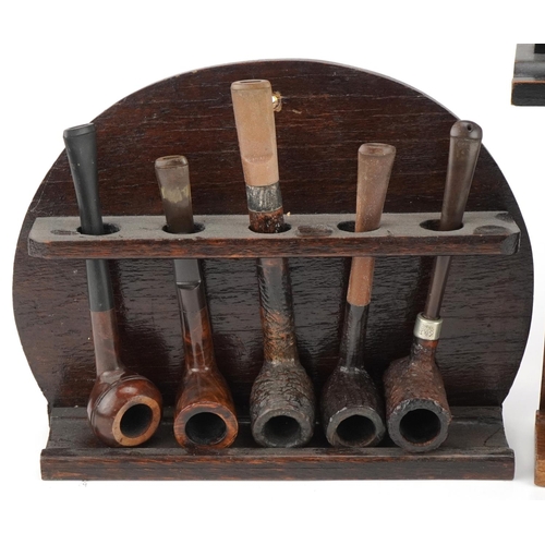 1277 - Twenty vintage briar tobacco smoking pipes arranged in four pipe stands including one in the form of... 