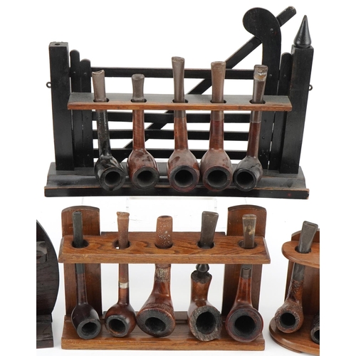 1277 - Twenty vintage briar tobacco smoking pipes arranged in four pipe stands including one in the form of... 