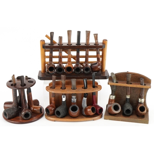 1292 - Twenty vintage tobacco smoking pipes, predominantly briar arranged in four pipe racks including one ... 