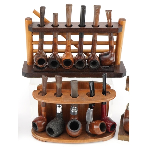 1292 - Twenty vintage tobacco smoking pipes, predominantly briar arranged in four pipe racks including one ... 