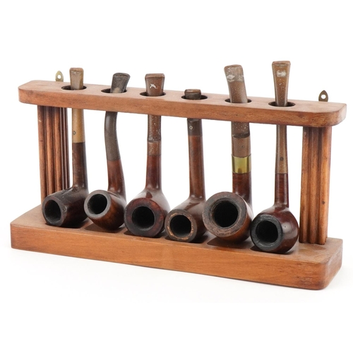 1261 - Six vintage Orlik Deluxe tobacco smoking pipes arranged in a lightwood pipe rack, the rack 28cm wide