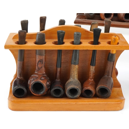 1270 - Twenty four briar tobacco smoking pipes arranged in three pipe racks including a double sided exampl... 