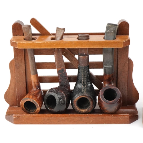 1276 - Twenty two vintage tobacco smoking pipes, predominantly briar, arranged in four pipe racks including... 