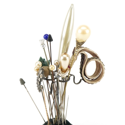 622 - Silver hatpin stand housing various hatpins including simulated pearl and sequinned examples, the st... 