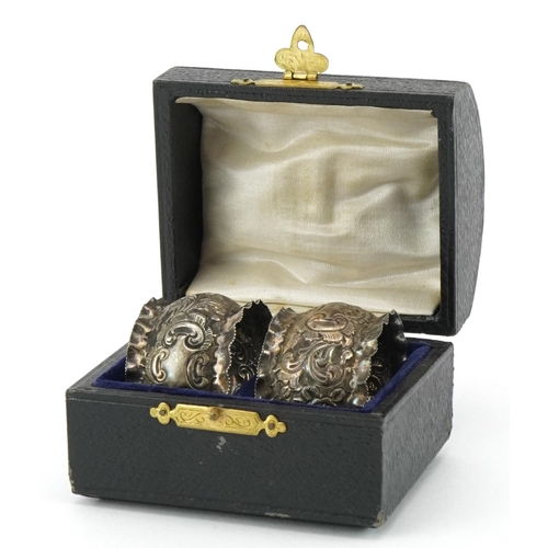 690 - J Sherwood & Sons, pair of Victorian silver napkin rings embossed with flowers and foliage, housed i... 