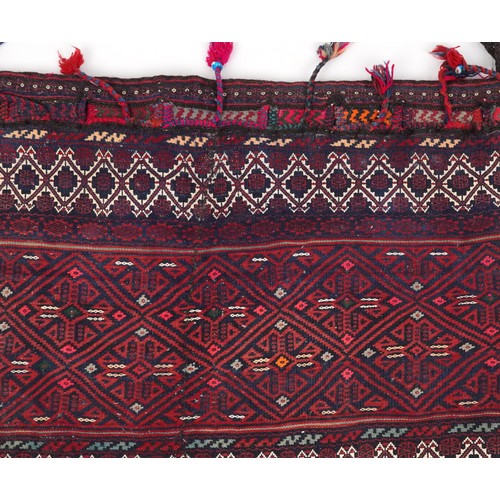 2207 - Rectangular Afghan red ground saddle bag having an allover repeat design, 150cm x 80cm