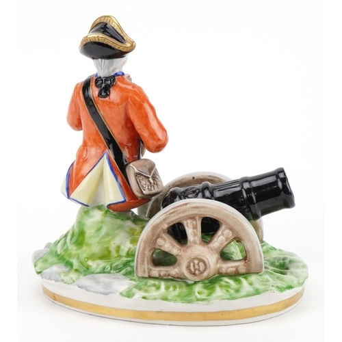 2450 - Naples porcelain figure of a Napoleonic soldier sitting beside a cannon, 17.5cm wide