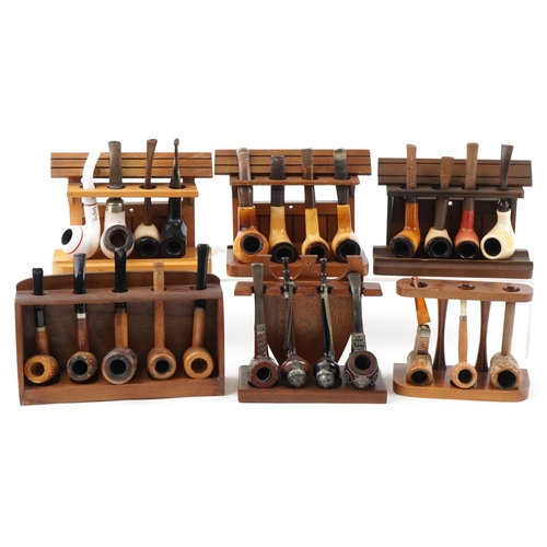 1281 - Twenty five vintage tobacco smoking pipes arranged in six pipe racks the pipes including block Meers... 