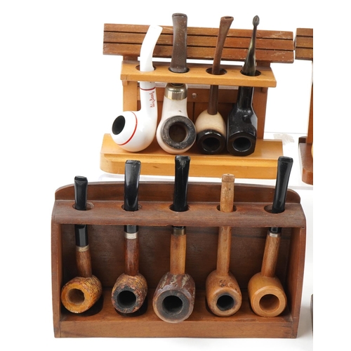 1281 - Twenty five vintage tobacco smoking pipes arranged in six pipe racks the pipes including block Meers... 