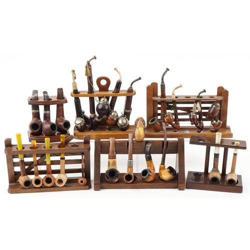 1296 - Twenty one vintage tobacco smoking pipes arranged in six pipe racks, two in the form of a gate, the ... 