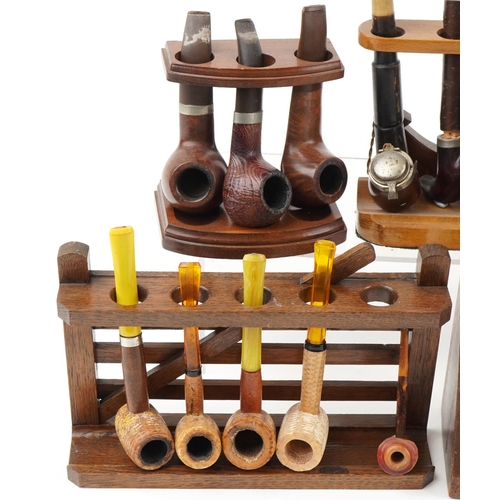 1296 - Twenty one vintage tobacco smoking pipes arranged in six pipe racks, two in the form of a gate, the ... 