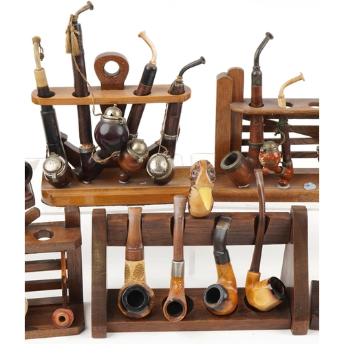 1296 - Twenty one vintage tobacco smoking pipes arranged in six pipe racks, two in the form of a gate, the ... 